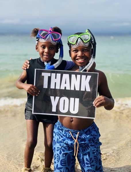 Two iOcean Trust participants holding a thank-you sign on the beach